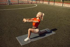 Beautiful blonde doing stretching on the lawn of a football field photo