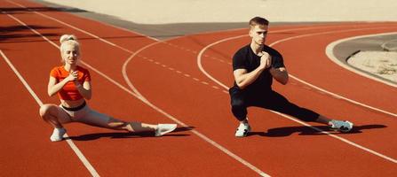 girl and a guy doing a warm-up before sports exercises at the school stadium photo