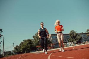 joven pareja deportiva corriendo en el estadio en la pista de atletismo foto