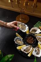 open fresh oysters on a metal plate in ice on a concrete background photo