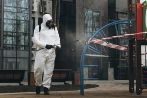 Cleaning and Disinfection on the playground in the sity complex amid the coronavirus epidemic Teams for disinfection efforts Infection prevention and control of epidemic Protective suit and mask photo