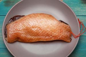 Meat, protein. A piece of dry-cured duck on a gray plate on an old turquoise board. photo