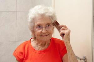 anciana peinándose frente a un espejo en el baño
