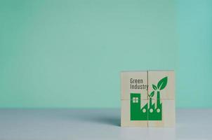 Wooden cube with industrial factory icon and green industrial font. Eco-friendly business and development concept on background. photo