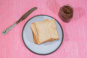 Whole wheat bread loaf slice in plate have chocolate on pink background photo