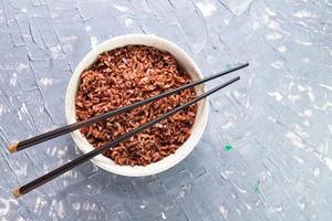 arroz rojo en un recipiente aislado sobre fondo gris. comida asiática cocinada. foto