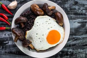 comida saludable arroz negro en un tazón con champiñones con huevo frito ajo chili hierba foto