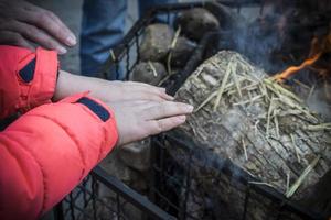 un niño calentándose las manos sobre un fuego durante el invierno foto