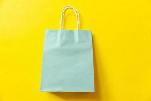 Simply minimal design shopping bag isolated on yellow background. Online or mall shopping shopaholic concept. Black friday Christmas season sale. Flat lay top view copy space, mock up photo