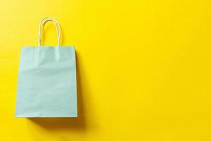 Simply minimal design shopping bag isolated on yellow background. Online or mall shopping shopaholic concept. Black friday Christmas season sale. Flat lay top view copy space, mock up photo