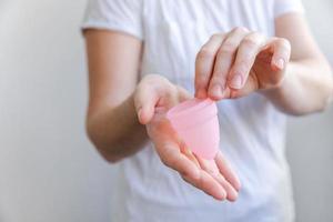 Woman hand holding pink menstrual cup isolated on white background. Woman modern alternative eco gynecological hygiene in menstruation period. Container for blood in girl hand. photo