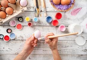 Female hands coloring easter eggs with pastel paints, top view flat lay photo