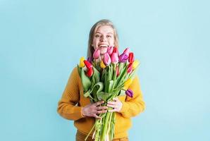 pretty charming young woman dressed yellow clothes holding tulip bunch isolated blue color background photo