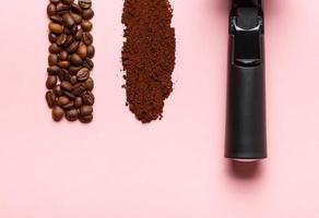 Detail of espresso machine filter holder, ground coffee and coffee beans on pink background. Space for text. photo