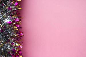 pink background with christmas tinsel from the left side photo