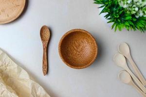 utensilios de madera en la mesa de la cocina. platos redondos de madera, cucharas de madera, una planta verde. el concepto de servir, cocinar, cocinar, detalles interiores. vista superior foto