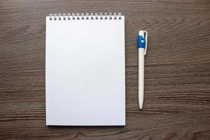 notebook and pen on wooden background photo