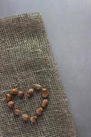 Nuts laid out in the shape of a heart on burlap with gray background. Organic, healthy food, ecology, farm photo