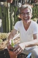 senior asian man laughing with happiness while planting succulent plant photo