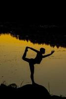 siluetas de una mujer haciendo yoga al atardecer foto