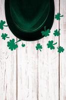 Leprechaun hat and shamrock clover leaves on white background. photo