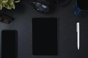 top view working desk with keyboard headphone and tablet on black table background photo