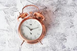 hermoso reloj despertador vintage hecho de metal dorado sobre una superficie de textura blanca. Buenos días. despertar. vista superior foto