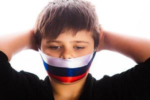 Clouse-up portrait of a boy covers his face with ribbons with flag of Russia. escalation of Ukraine