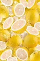 agua salpicada en rodajas de limón aislado en fondo amarillo foto