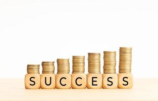 Success concept. Wooden blocks with text and rising stacked coins. Copy space photo