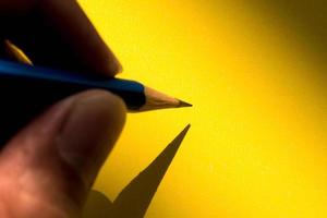 mano humana sosteniendo un lápiz para escribir en el papel a la sombra foto