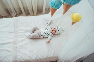 Newborn baby dressed in a white suit and black stars is a white soft bed in the studio photo