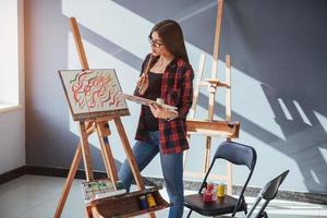 Pretty Pretty Girl artist paints on canvas painting on the easel. photo