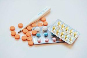 Flu. Thermometer with elevated temperature and many pills on light background photo