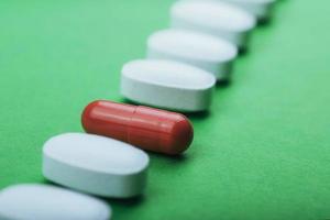 Medical white pills and brown capsules for the treatment and health care on a green background photo