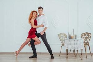 Young beautiful woman in a red dress and a man dancing, isolated on a white background. photo
