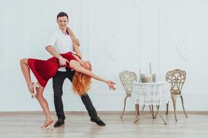 Young beautiful woman in a red dress and a man dancing, isolated on a white background. photo