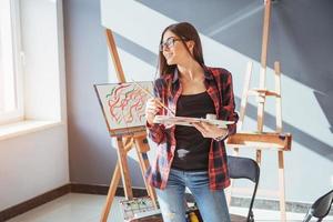 Pretty Pretty Girl artist paints on canvas painting on the easel. photo