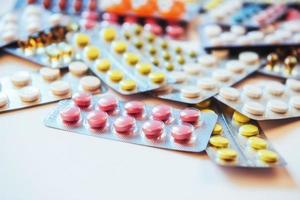 Pills of different colors lie on the surface in a sealed package. photo