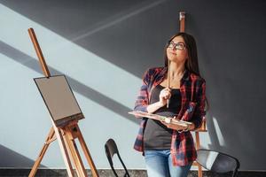 Young woman artist painting a picture in studio photo