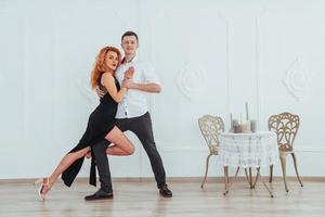 Young beautiful woman in a black dress and a man in white shirt dancing. photo