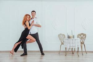 joven mujer hermosa con un vestido negro y un hombre con camisa blanca bailando. foto