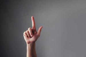 Close up view of the human hand, touching his index finger on a gray background. Valet touchscreen. Pointing at something. Body Language. photo
