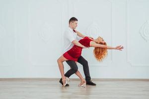 joven hermosa mujer con un vestido rojo y un hombre bailando, aislado en un fondo blanco. foto