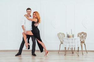 Young beautiful woman in a black dress and a man in white shirt dancing. photo