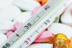 termómetro y diferentes tipos de pastillas de colores. concepto de salud médica o drogas foto