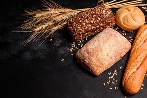 Beautiful fresh baked bread with wheat grains on a dark concrete background photo