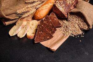 hermoso pan recién horneado con granos de trigo sobre un fondo de hormigón oscuro foto