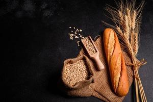 Beautiful fresh baked bread with wheat grains on a dark concrete background