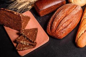 Beautiful fresh baked bread with wheat grains on a dark concrete background photo